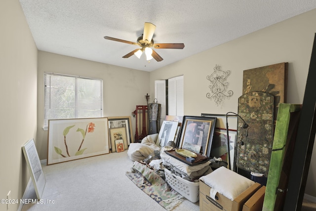 interior space with a textured ceiling, light carpet, and ceiling fan