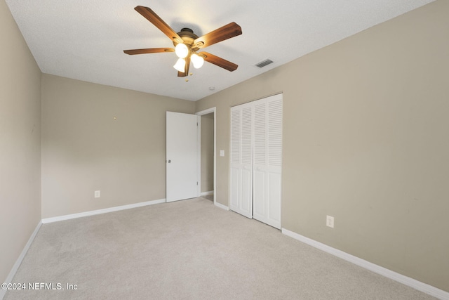 unfurnished bedroom with a closet, a textured ceiling, light colored carpet, and ceiling fan