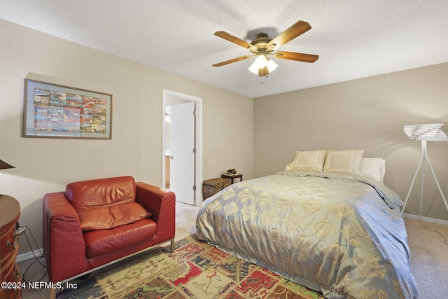 carpeted bedroom featuring a textured ceiling, ensuite bathroom, and ceiling fan