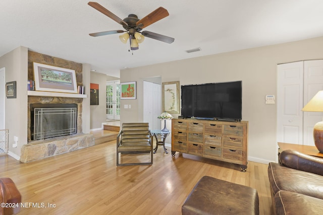 living room featuring a fireplace, light hardwood / wood-style flooring, and ceiling fan