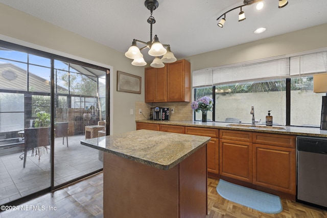 kitchen featuring stainless steel dishwasher, a healthy amount of sunlight, sink, and pendant lighting