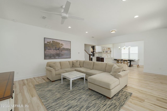 living room with ceiling fan with notable chandelier and light wood-type flooring