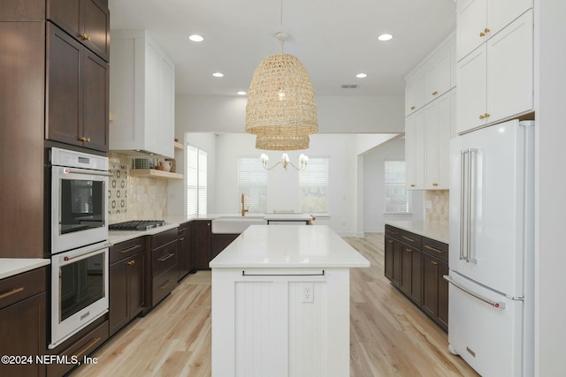 kitchen featuring a center island, stainless steel appliances, hanging light fixtures, and light hardwood / wood-style flooring