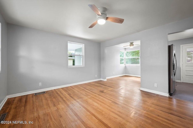 empty room with hardwood / wood-style floors, a wealth of natural light, and ceiling fan