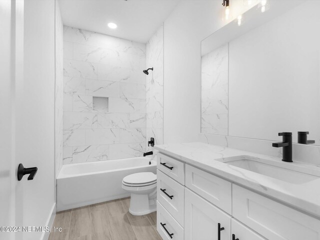 full bathroom featuring toilet, tiled shower / bath combo, vanity, and wood-type flooring