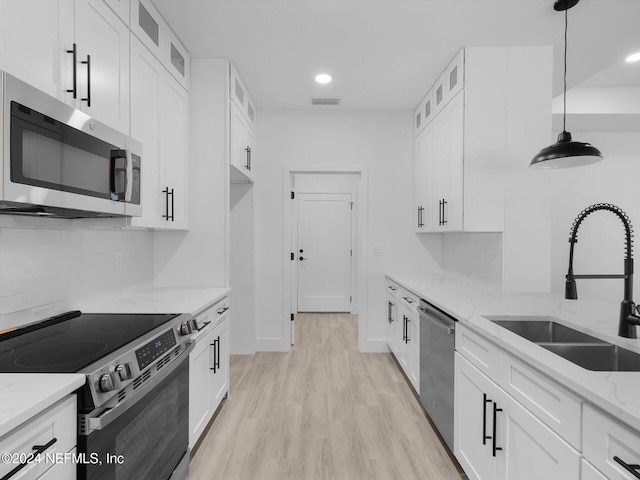 kitchen with white cabinets, stainless steel appliances, hanging light fixtures, and sink