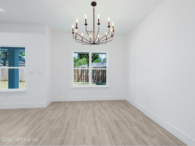 unfurnished dining area featuring light hardwood / wood-style floors and a chandelier