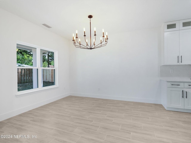 unfurnished dining area featuring a notable chandelier and light hardwood / wood-style floors