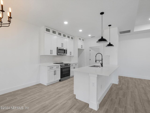 kitchen featuring stainless steel appliances, hanging light fixtures, white cabinets, and sink