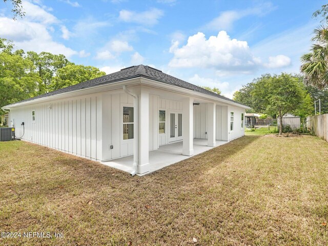 rear view of property featuring a lawn, cooling unit, and a patio area