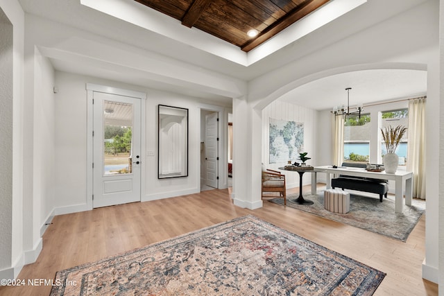 entrance foyer with light hardwood / wood-style floors, a chandelier, and wood ceiling