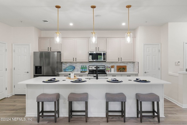 kitchen featuring a kitchen bar, appliances with stainless steel finishes, and a center island with sink