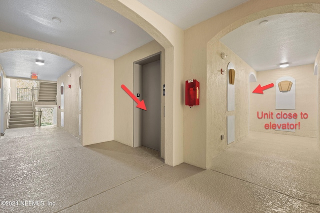 hall featuring elevator and a textured ceiling