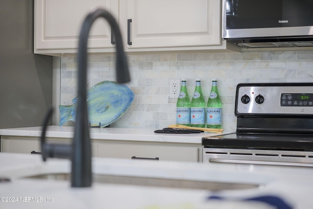 kitchen with white cabinetry, decorative backsplash, and appliances with stainless steel finishes