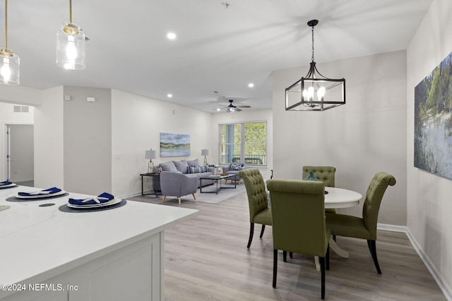 dining area with light wood-type flooring and ceiling fan with notable chandelier