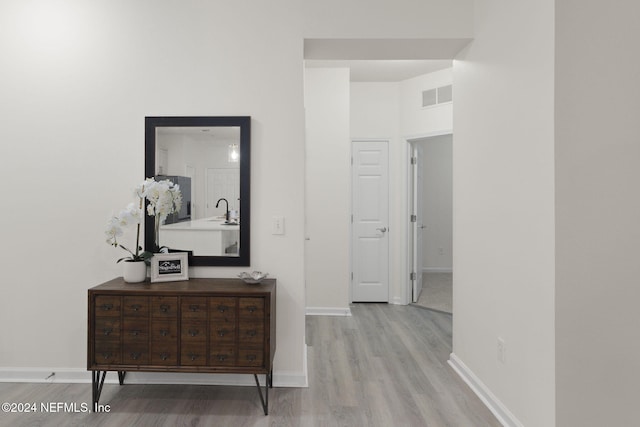 hallway with light wood-type flooring and sink