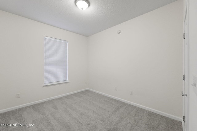 carpeted empty room featuring a textured ceiling