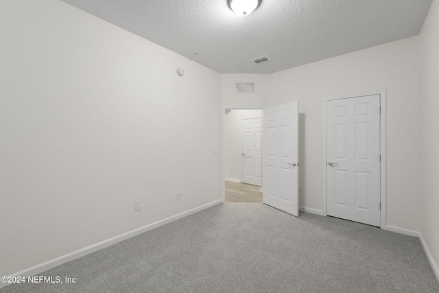 unfurnished bedroom with a textured ceiling and light colored carpet