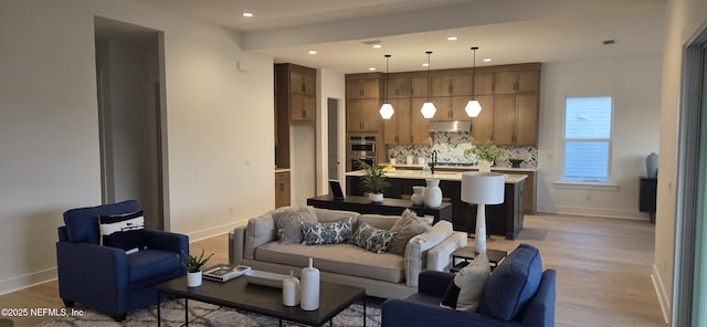 living area featuring light wood-style floors, recessed lighting, and baseboards