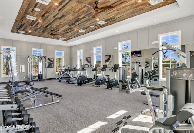 exercise room featuring ceiling fan, wood ceiling, a decorative wall, and a raised ceiling