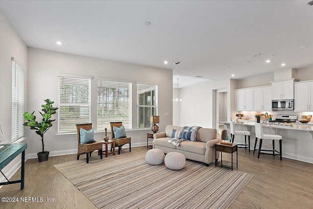 living room featuring light hardwood / wood-style floors, sink, and an inviting chandelier