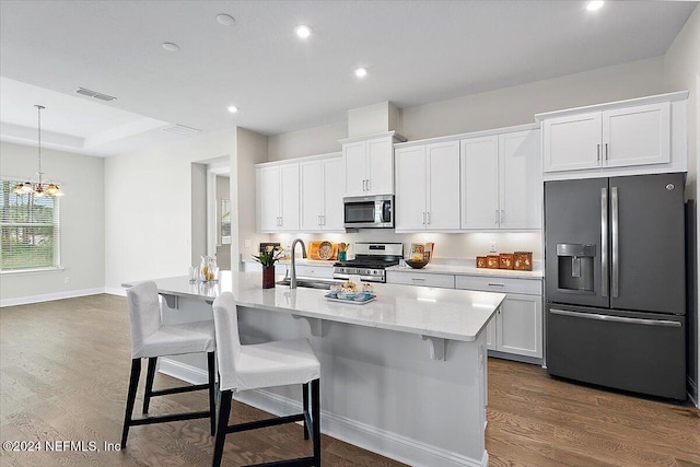 kitchen featuring dark wood-type flooring, a center island with sink, white cabinets, sink, and appliances with stainless steel finishes