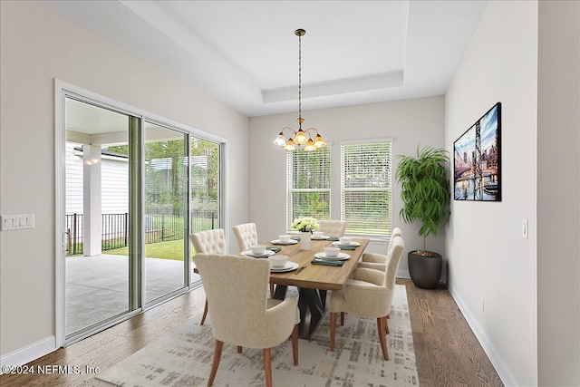 dining space featuring hardwood / wood-style floors, a chandelier, and a tray ceiling