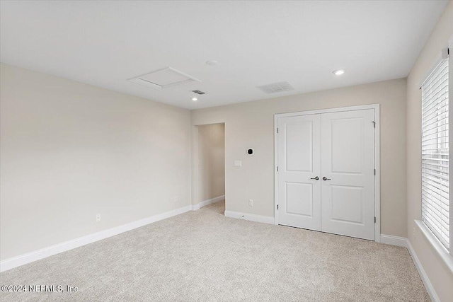 unfurnished bedroom featuring light carpet, multiple windows, and a closet