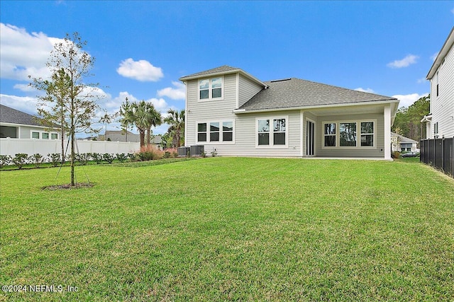 rear view of property with cooling unit and a lawn