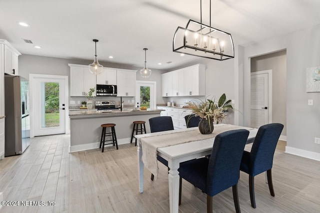 dining space featuring light wood-type flooring, sink, and a chandelier