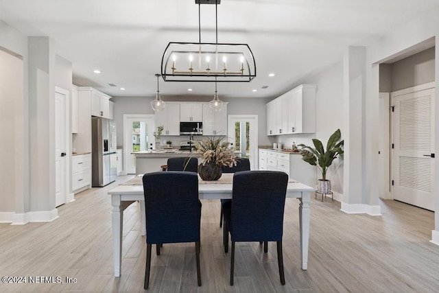 dining area featuring light wood-type flooring and an inviting chandelier