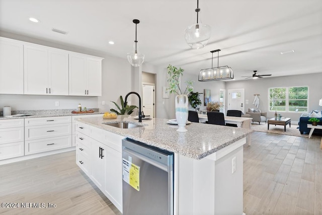 kitchen featuring stainless steel dishwasher, sink, pendant lighting, and an island with sink