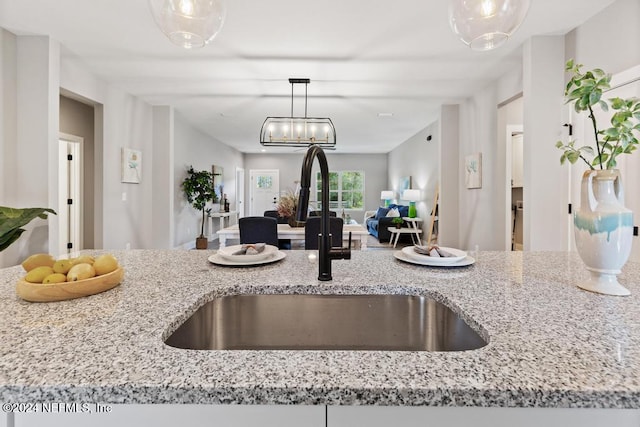 kitchen with sink, pendant lighting, and light stone counters