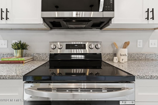 kitchen featuring white cabinetry, stainless steel appliances, and light stone counters