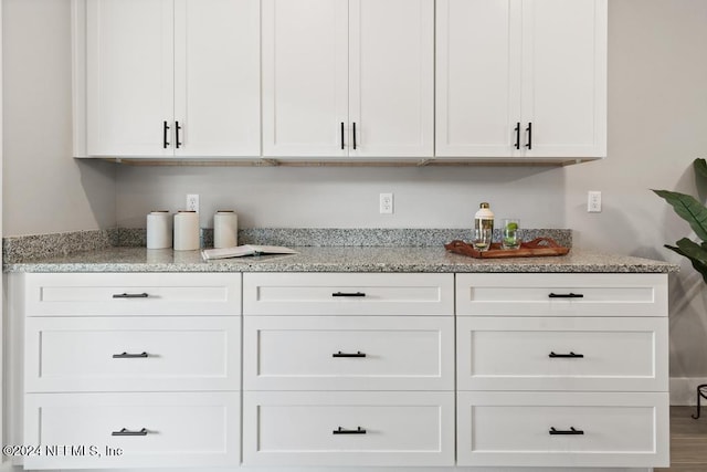 bar with white cabinets and wood-type flooring