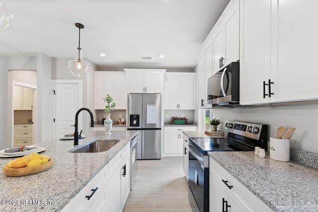 kitchen featuring light hardwood / wood-style flooring, sink, light stone countertops, white cabinetry, and appliances with stainless steel finishes