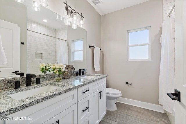 bathroom featuring toilet, vanity, curtained shower, and a healthy amount of sunlight