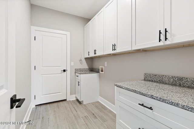 clothes washing area with cabinets, light hardwood / wood-style floors, and washer hookup