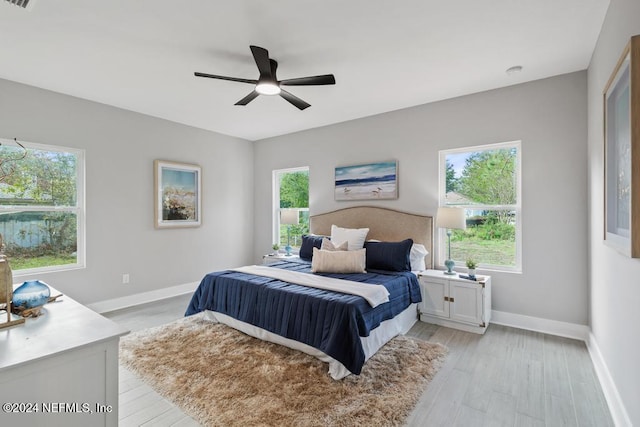 bedroom with ceiling fan, multiple windows, and light hardwood / wood-style floors