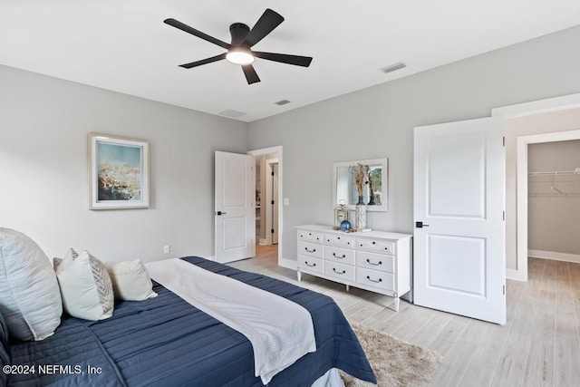 bedroom featuring a spacious closet, ceiling fan, light hardwood / wood-style flooring, and a closet