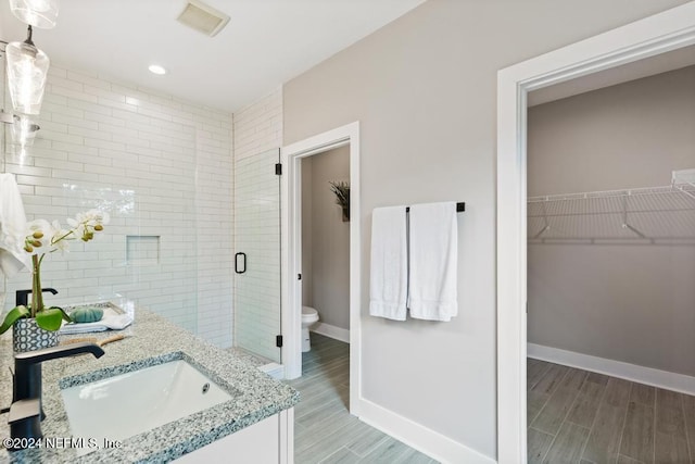 bathroom featuring a shower with shower door, vanity, and toilet