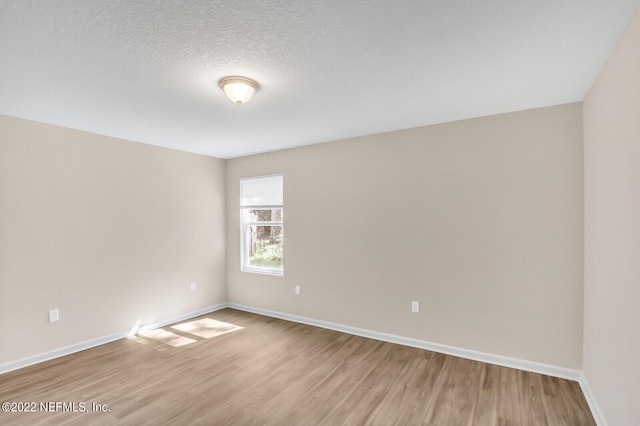 spare room with light wood-type flooring and a textured ceiling