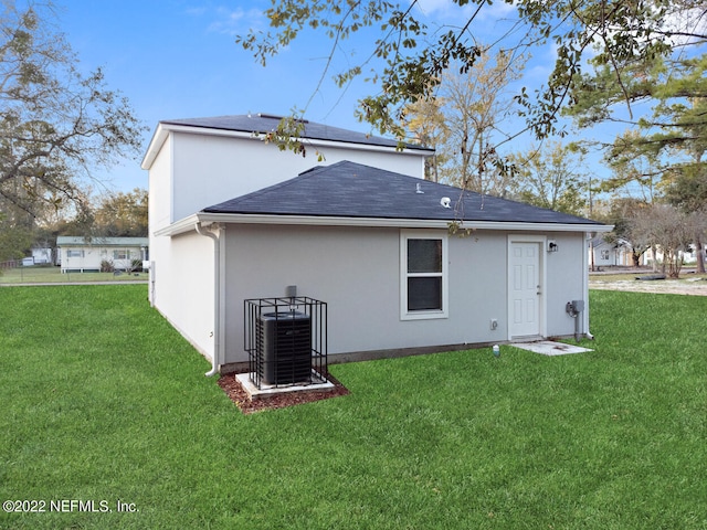 rear view of house featuring cooling unit and a lawn