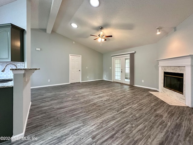 unfurnished living room featuring lofted ceiling with beams, ceiling fan, a high end fireplace, and dark hardwood / wood-style floors