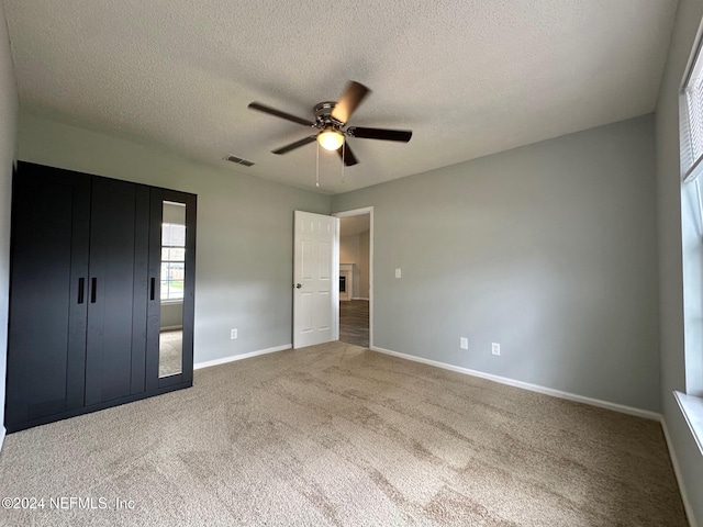 unfurnished bedroom featuring ceiling fan, a textured ceiling, and carpet flooring