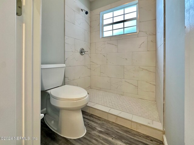 bathroom featuring hardwood / wood-style floors, tiled shower, and toilet