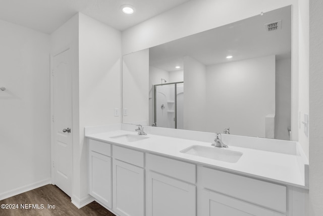 bathroom with hardwood / wood-style flooring, a shower with shower door, and vanity