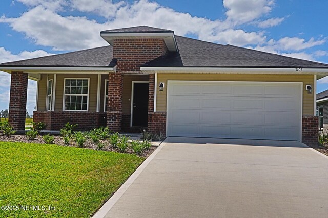 prairie-style home featuring brick siding, an attached garage, driveway, and a front yard