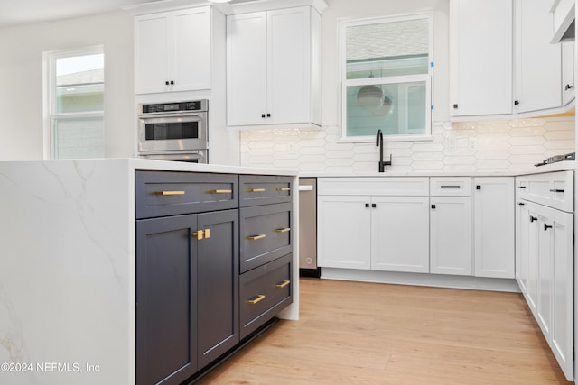 kitchen featuring white cabinets, decorative backsplash, light hardwood / wood-style floors, and sink