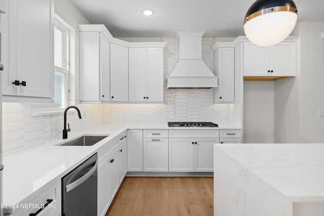 kitchen featuring dishwasher, sink, white cabinets, and custom exhaust hood